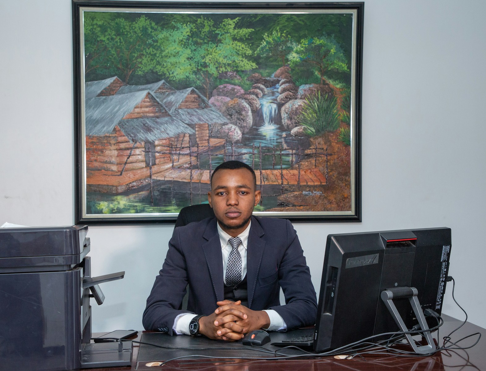 man in black suit jacket sitting on chair in front of black laptop computer